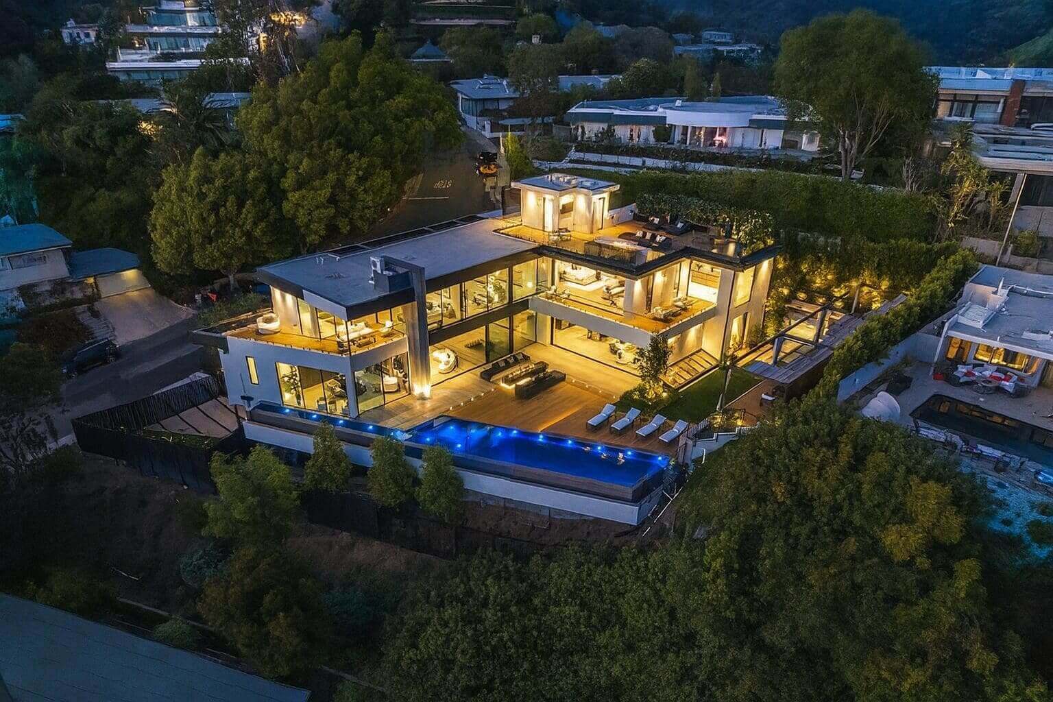 Luxury hillside mansion with pool at night.